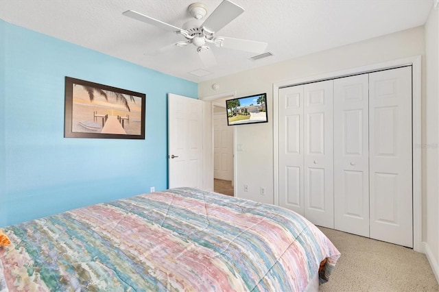 bedroom featuring visible vents, carpet flooring, a closet, a textured ceiling, and a ceiling fan