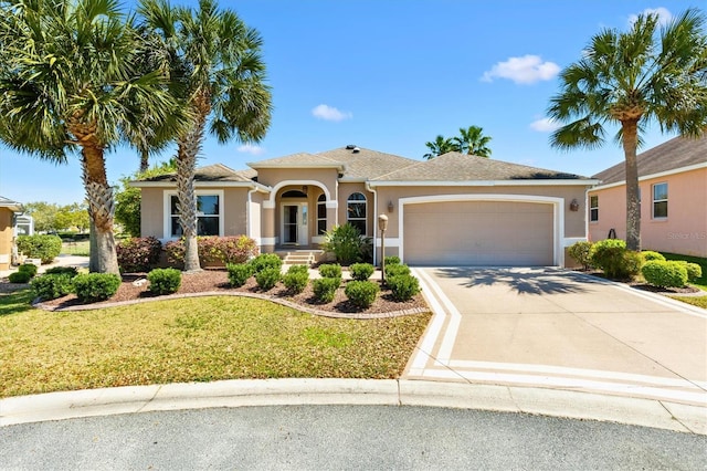 view of front of property featuring stucco siding, a front yard, an attached garage, and driveway