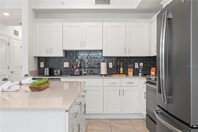 kitchen with light tile patterned floors, visible vents, stainless steel fridge, and white cabinetry