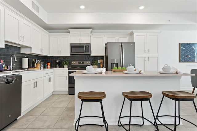 kitchen with visible vents, decorative backsplash, stainless steel appliances, white cabinetry, and a sink