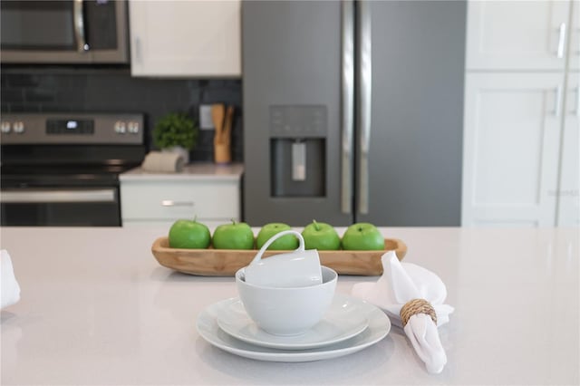 interior details featuring appliances with stainless steel finishes, light countertops, and white cabinetry