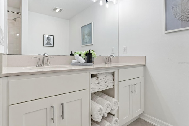 bathroom with double vanity, visible vents, baseboards, and a sink