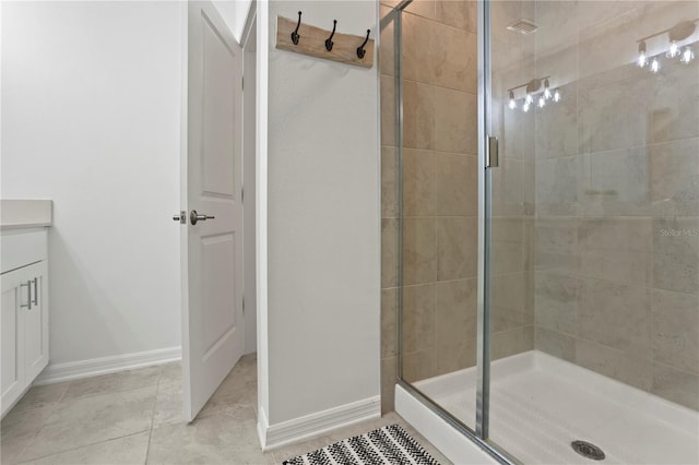 bathroom with baseboards, vanity, a shower stall, and tile patterned flooring