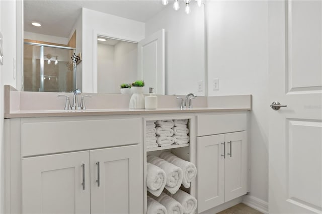 bathroom with double vanity, baseboards, a stall shower, and a sink