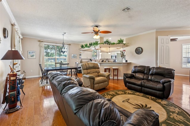 living room featuring visible vents, hardwood / wood-style floors, and crown molding