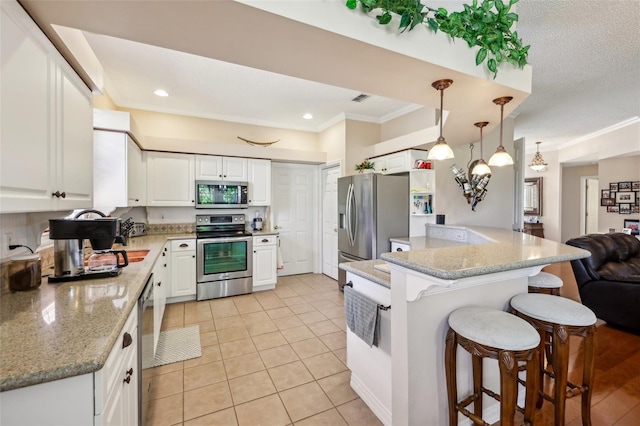 kitchen featuring a kitchen breakfast bar, appliances with stainless steel finishes, ornamental molding, and white cabinetry