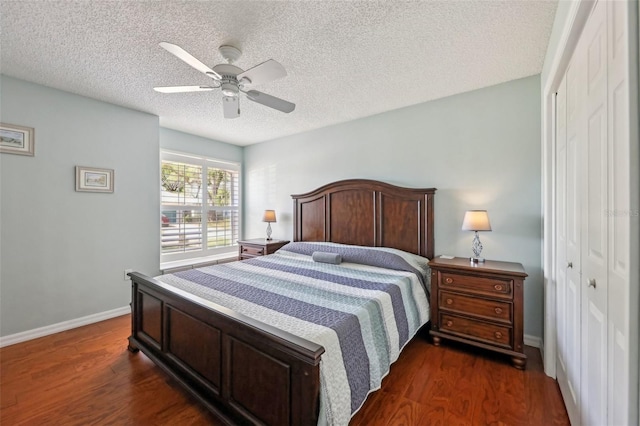 bedroom featuring dark wood-style floors, a textured ceiling, baseboards, and a closet