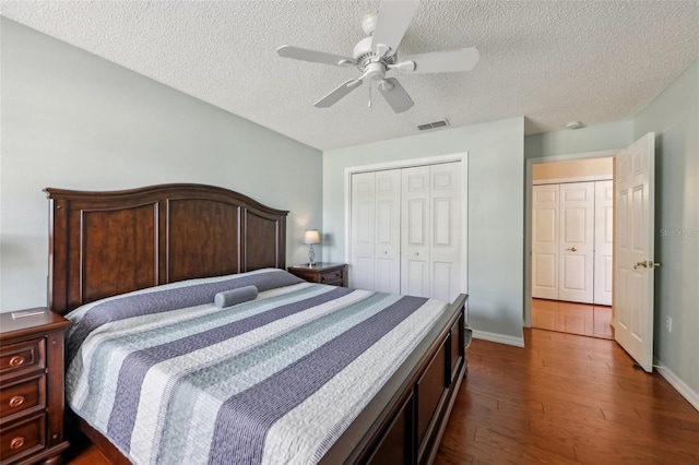 bedroom with a ceiling fan, visible vents, dark wood-style flooring, a closet, and a textured ceiling