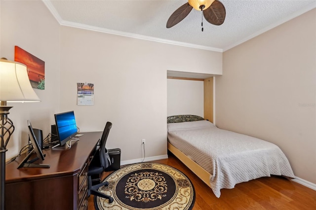 bedroom featuring baseboards, ceiling fan, ornamental molding, wood finished floors, and a textured ceiling