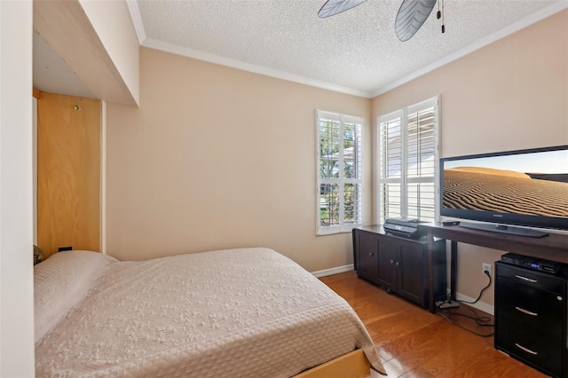 bedroom featuring baseboards, a textured ceiling, crown molding, and light wood-style floors