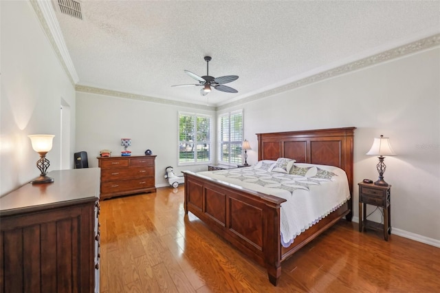 bedroom with baseboards, a textured ceiling, light wood-style floors, and ornamental molding