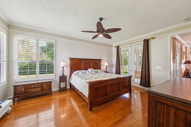 bedroom featuring light wood-style flooring, ornamental molding, access to exterior, french doors, and a textured ceiling