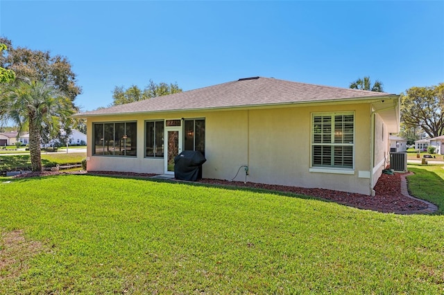 rear view of property with stucco siding, a lawn, and central AC unit