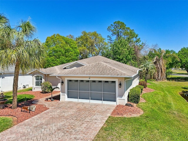 single story home with a shingled roof, a front yard, stucco siding, decorative driveway, and a garage