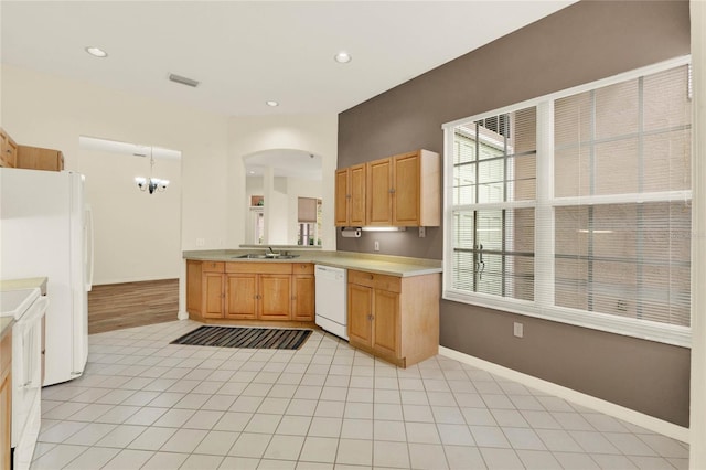 kitchen featuring visible vents, a sink, white appliances, light countertops, and baseboards