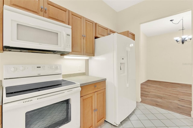 kitchen featuring light tile patterned floors, white appliances, an inviting chandelier, and light countertops