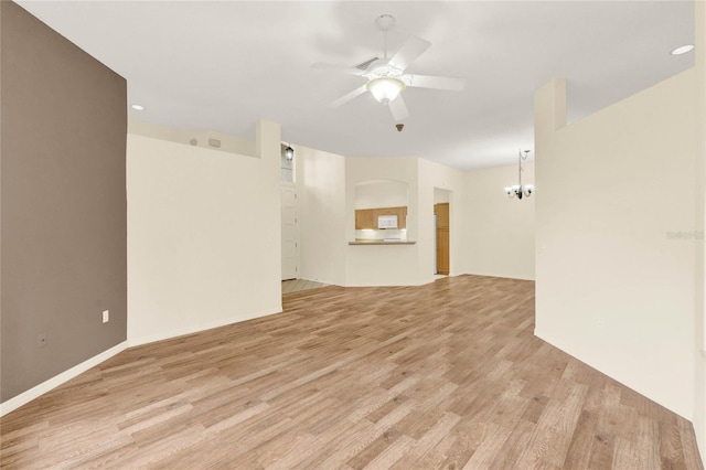 spare room with light wood-style floors and ceiling fan with notable chandelier