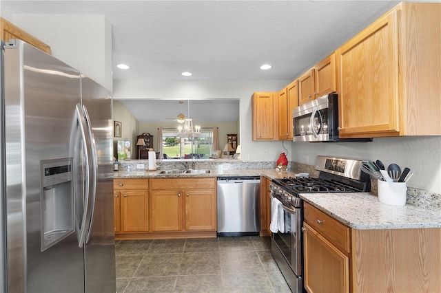 kitchen featuring light stone countertops, dark tile patterned flooring, recessed lighting, a sink, and appliances with stainless steel finishes