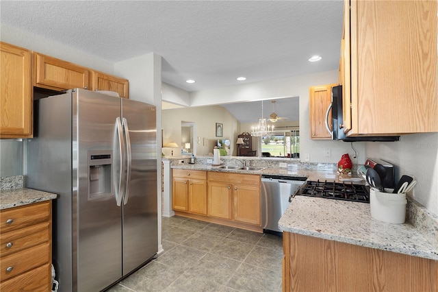 kitchen with light stone countertops, recessed lighting, a textured ceiling, stainless steel appliances, and a sink