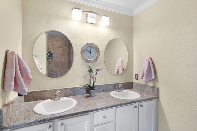 bathroom with a sink, double vanity, crown molding, and a textured wall