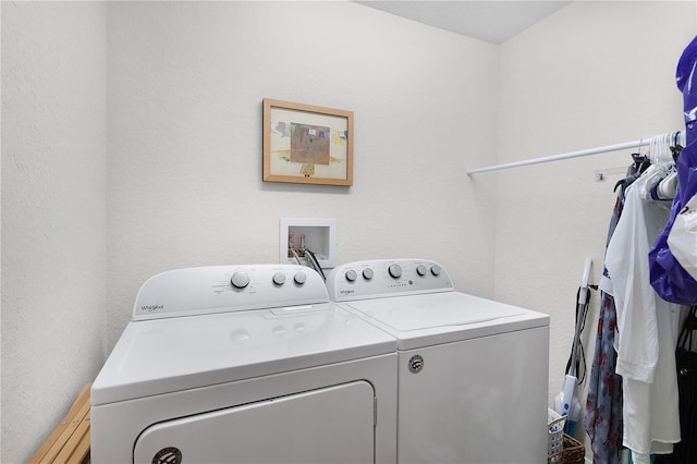 clothes washing area featuring laundry area, washing machine and dryer, and a textured wall