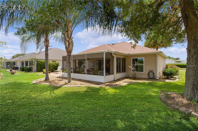 rear view of property featuring a yard, a sunroom, and stucco siding