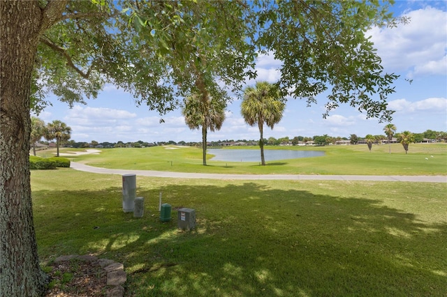 surrounding community with a water view and a lawn