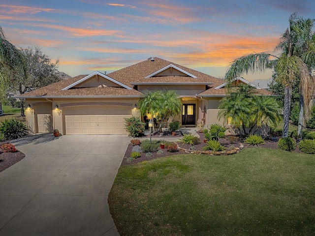 view of front of home featuring stucco siding, a front lawn, concrete driveway, an attached garage, and a shingled roof