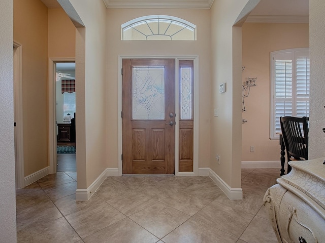 foyer with light tile patterned floors, crown molding, and baseboards