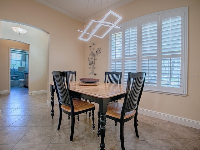 dining area with crown molding, light tile patterned flooring, baseboards, and arched walkways