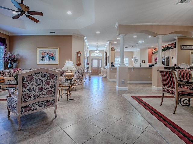 living area featuring light tile patterned floors, visible vents, decorative columns, ceiling fan, and ornamental molding