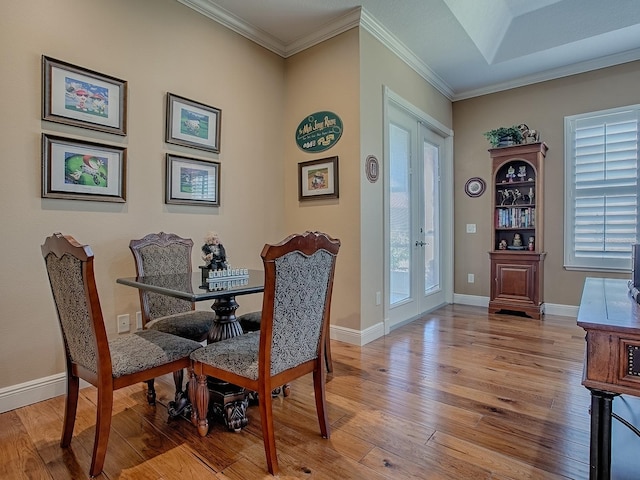 dining room with crown molding, light wood-type flooring, and baseboards