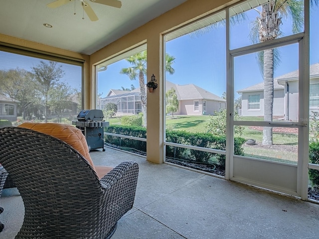 sunroom with a residential view and a ceiling fan