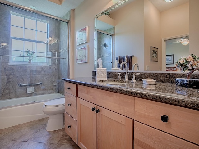 full bathroom with tile patterned flooring, toilet, combined bath / shower with glass door, vanity, and a ceiling fan