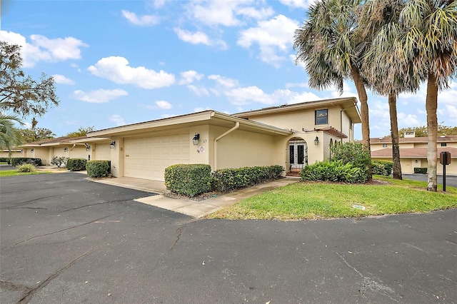 view of front of house featuring stucco siding, french doors, an attached garage, and driveway