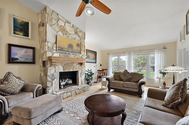 living room with a stone fireplace, lofted ceiling, wood finished floors, and a ceiling fan