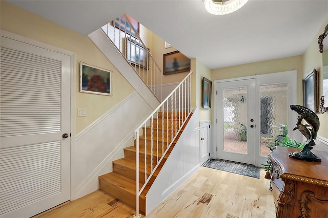 entryway with french doors, wood finished floors, and stairs