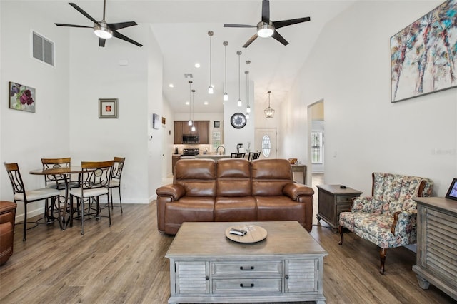 living room with visible vents, high vaulted ceiling, wood finished floors, and a ceiling fan