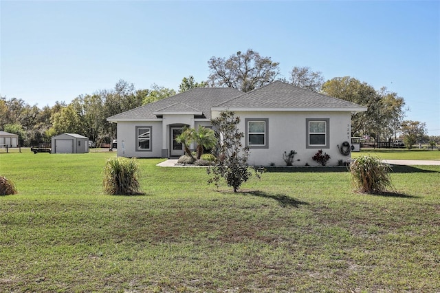 view of front of home featuring stucco siding, an outbuilding, a storage shed, and a front lawn