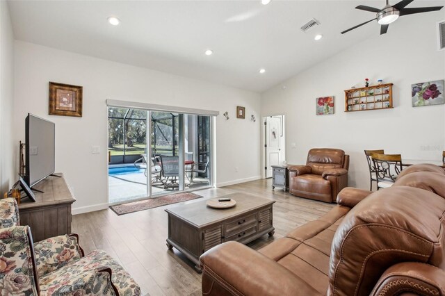 living area featuring light wood finished floors, visible vents, recessed lighting, and vaulted ceiling