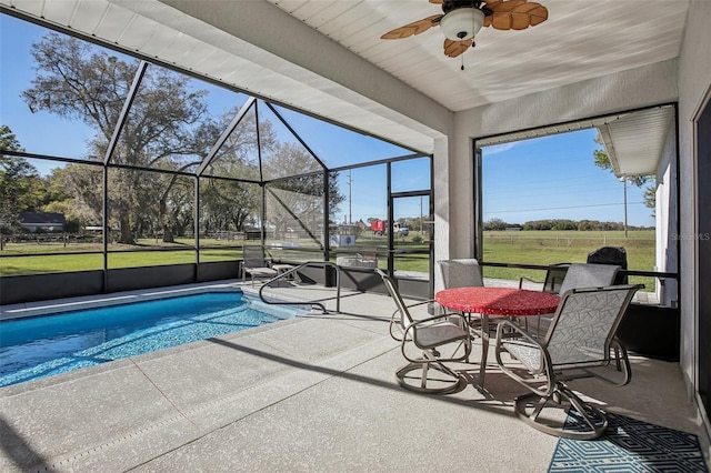 outdoor pool with a yard, glass enclosure, a patio, and ceiling fan