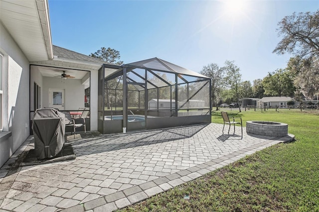 view of patio with glass enclosure, a fire pit, and an outdoor pool