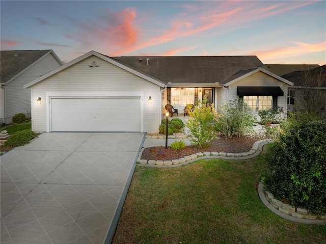 ranch-style home featuring an attached garage, concrete driveway, a front yard, and roof with shingles