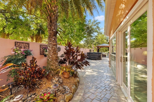 view of patio with a gazebo, a fenced backyard, and a hot tub