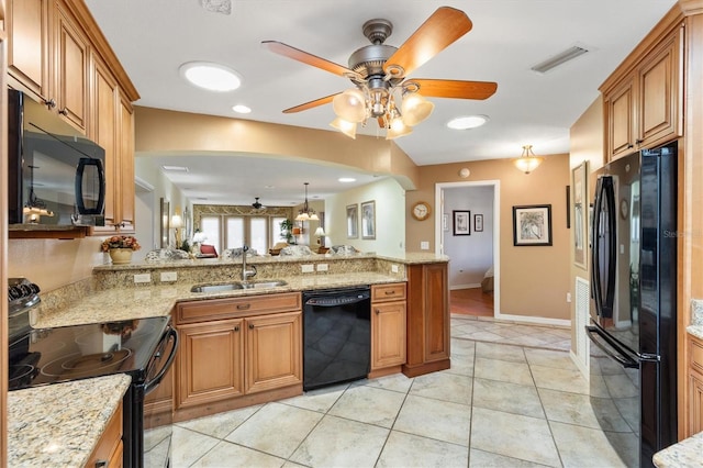 kitchen featuring visible vents, a peninsula, brown cabinetry, black appliances, and a sink