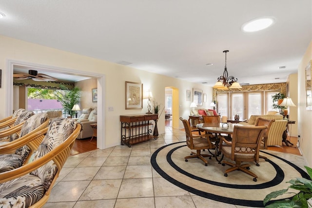 dining area with arched walkways, a chandelier, a healthy amount of sunlight, and light tile patterned flooring