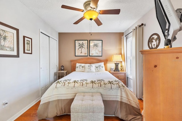 bedroom featuring baseboards, wood finished floors, a closet, and a textured ceiling