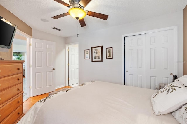 bedroom featuring visible vents, wood finished floors, a closet, a textured ceiling, and a ceiling fan