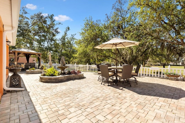 view of patio featuring a gazebo, outdoor dining area, and fence