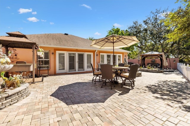 view of patio with outdoor dining space, a gazebo, french doors, and fence